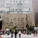 Pedestres caminham em uma rua movimentada diante do edifício Gazeta, na Avenida Paulista, em São Paulo.