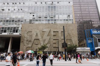 Pedestres caminham em uma rua movimentada diante do edifício Gazeta, na Avenida Paulista, em São Paulo.
