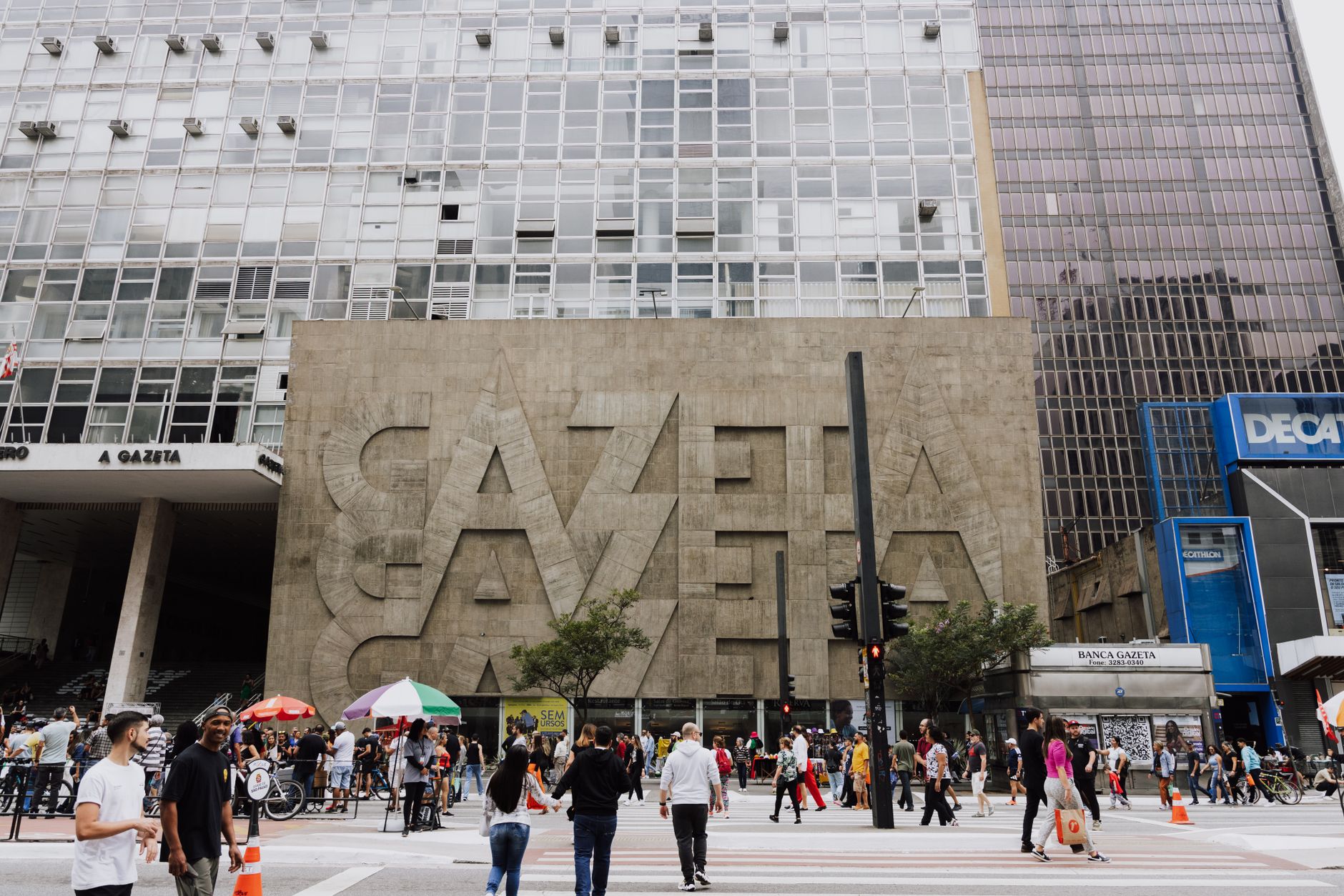 Pedestres caminham em uma rua movimentada diante do edifício Gazeta, na Avenida Paulista, em São Paulo.