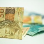 Cédula de 50 reais em destaque sobre outras notas brasileiras.
