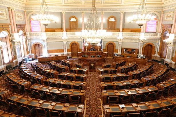 Vista ampla de um plenário legislativo ornamentado, com cadeiras vazias e lustres