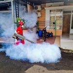 Profissional de controle de pragas utiliza uma máquina de fumaça para fumigar a área externa de uma casa.